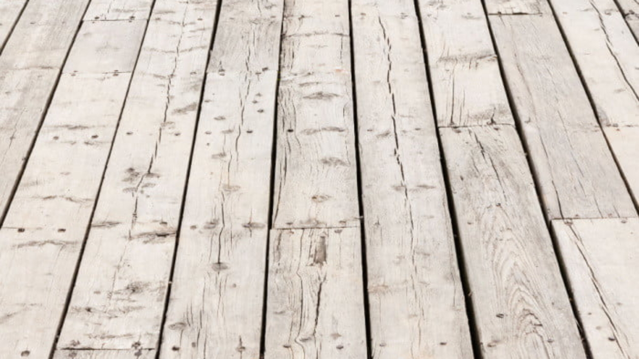 Cracked-weathered-gray-wooden-deck-surface-boards-due-to-sun-damage